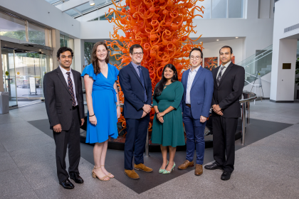 six people in formal dress in front of orange colored sculpture