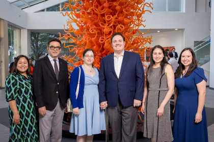 six people in formal dress in front of orange colored sculpture