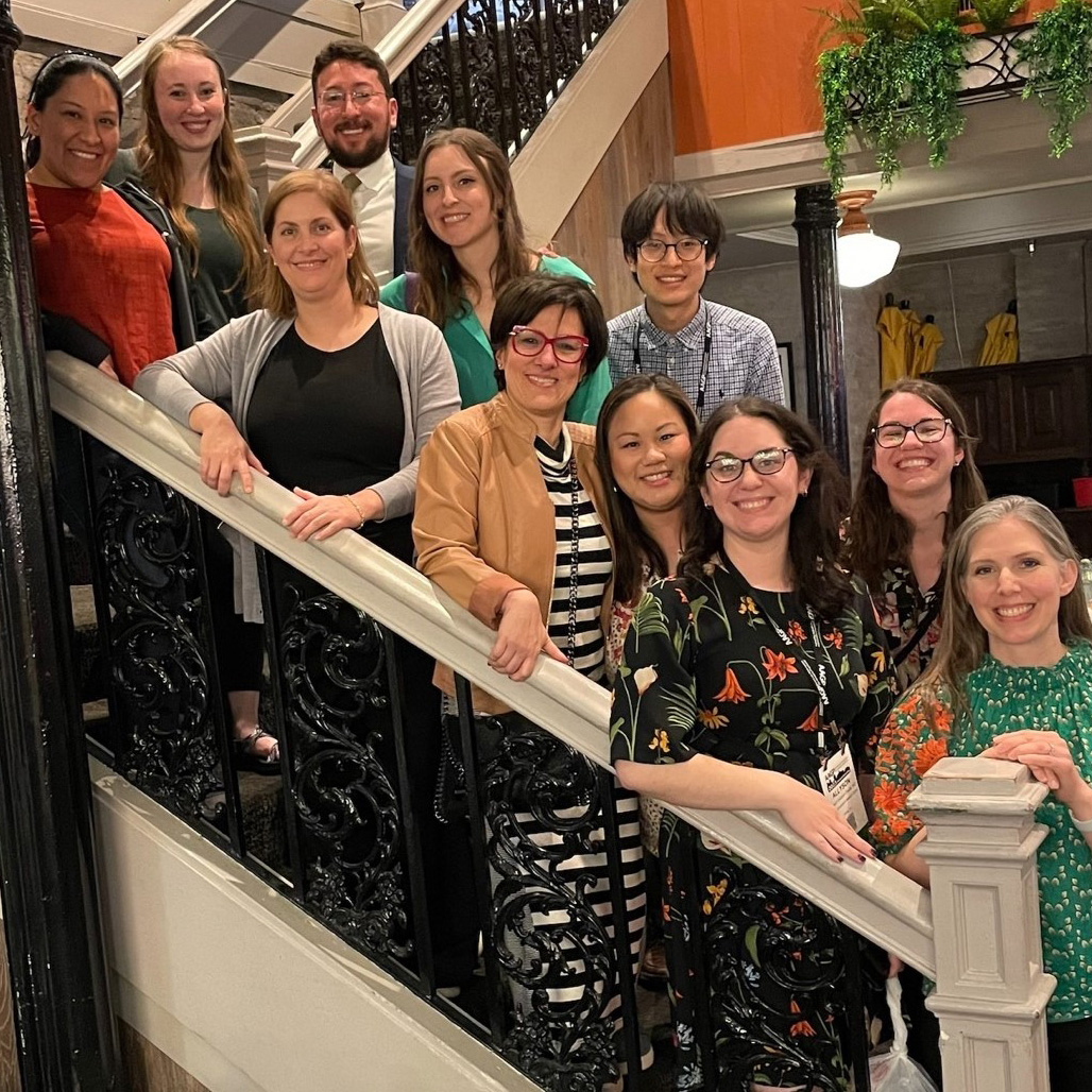 Group of 11 People pose along bannister on stairs