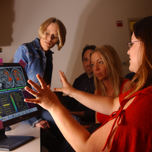 teacher talks with 3 medical students at looking at computer display