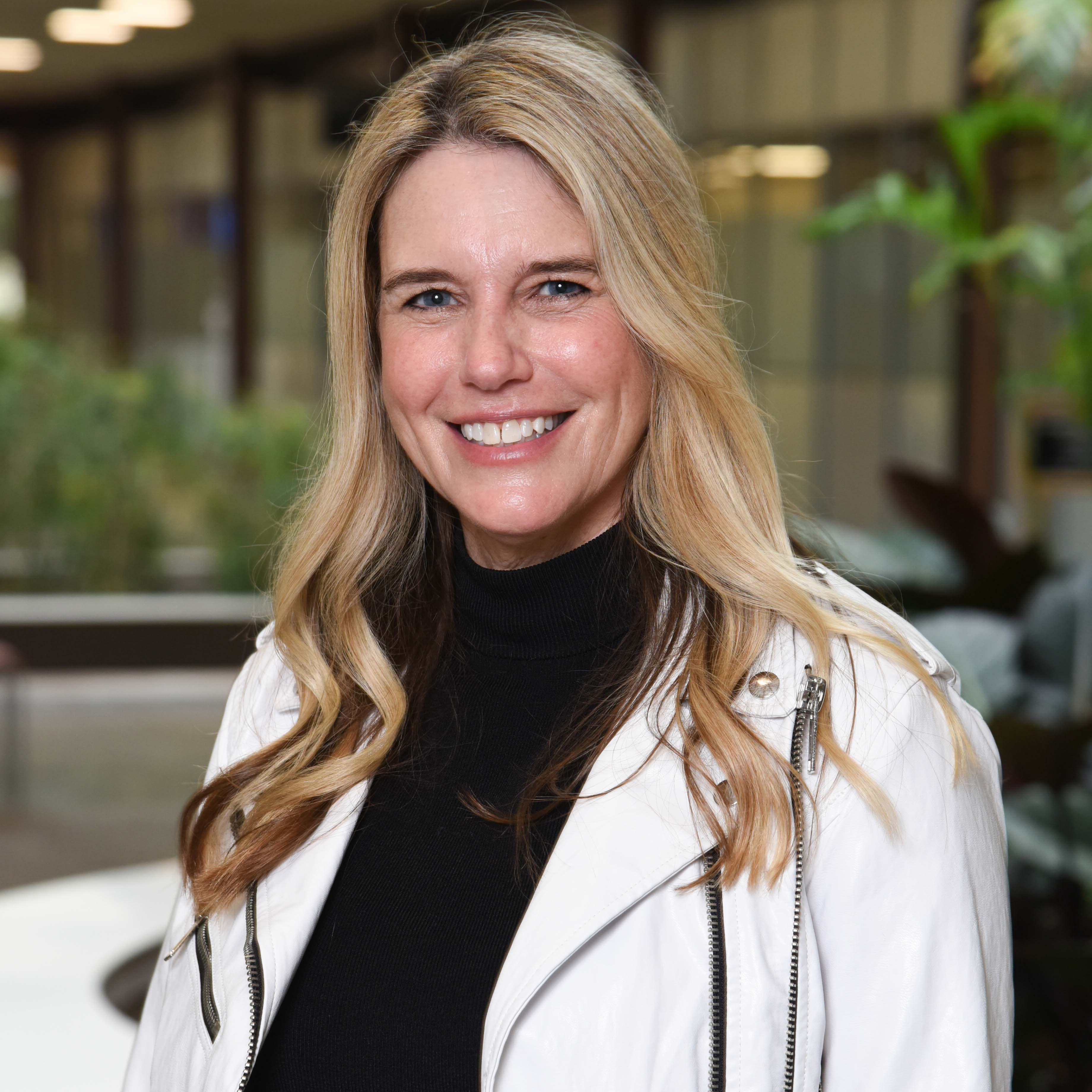 white woman with long blonde hair in white jacket and black sweater