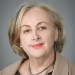 headshot of white woman with blonde hair wearing a tan jacket