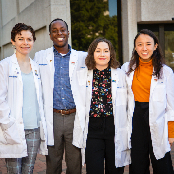 One male and three female medical students in their white coats