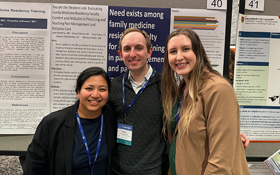 2 female and 1 male faculty in front of research poster