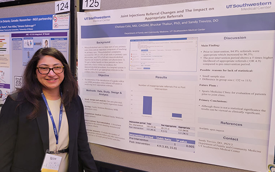 women standing next to a research poster