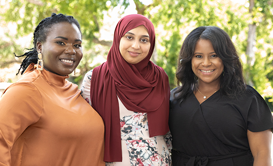 Three women standing outdoors wearing colorful closthing.