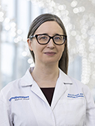 Woman with long, straight brown hair wearing a white coat with UT Southwestern Medical Center logo and black glasses