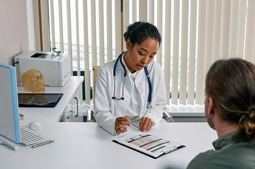 Woman wearing white coat filling out paperwork while patient looks on