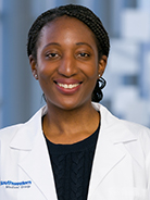 Woman with dark, braided hair wearing a black shirt and white coat with UT Southwestern Medical Center logo