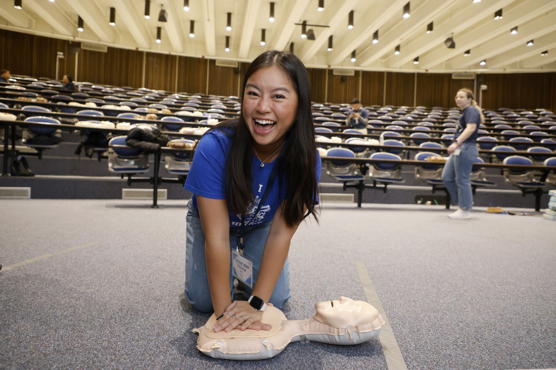 Young female student smiles for the camera as she practices CPR