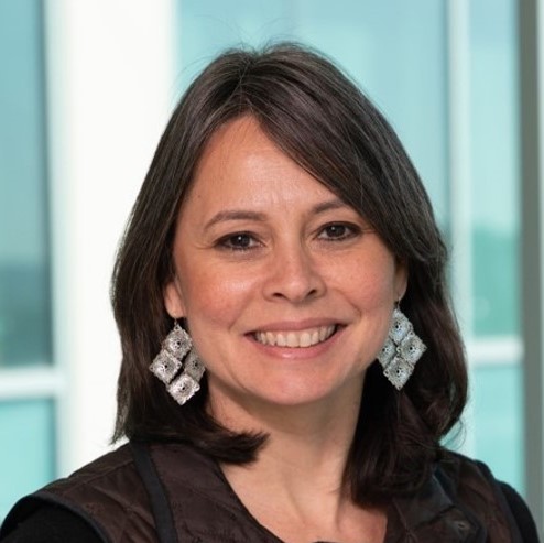 smiling woman with a dark top and light earrings