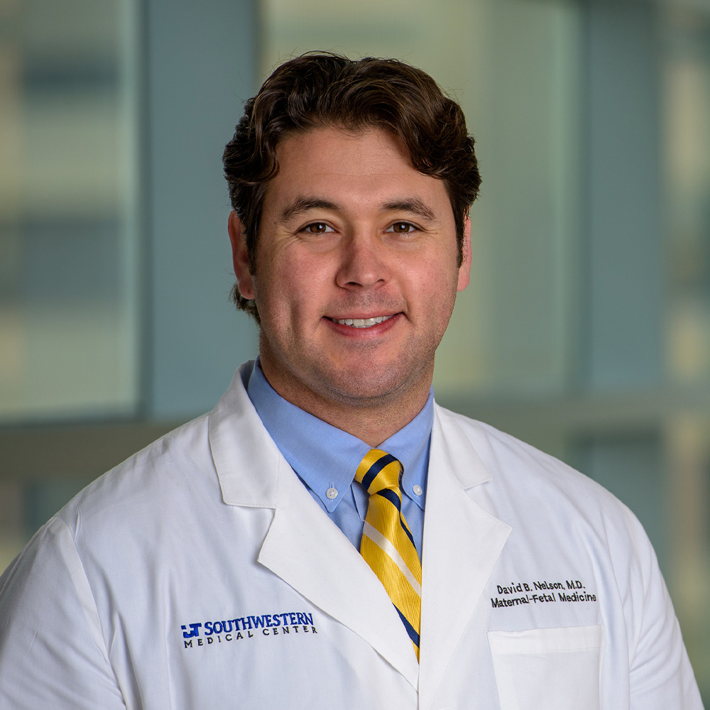 smiling male in a white lab coat with a blue shirt and yellow tie