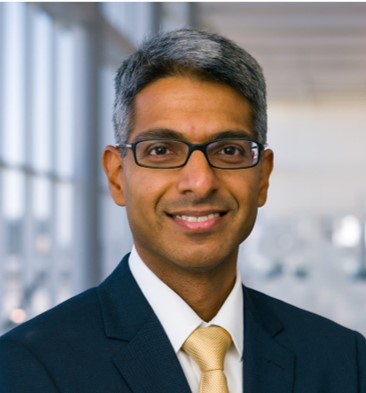 smiling man in a dark suit with a light tie