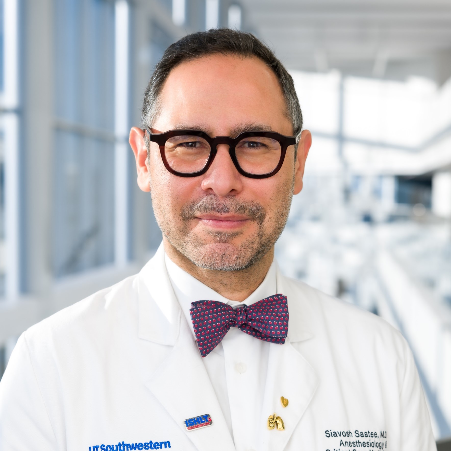 smiling man in a white lab coat with a dark bowtie