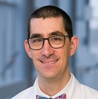 smiling man in a white coat with a colorful tie