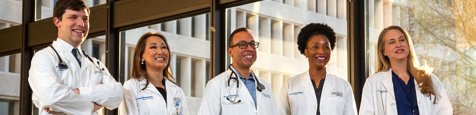 Three female and two male doctors in white coats