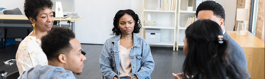 5 diverse people sit in group therapy circle