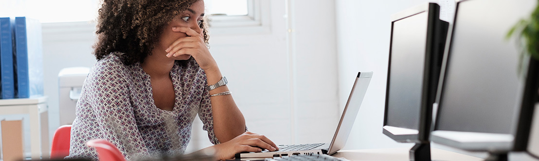 concerned woman sits in front of laptop