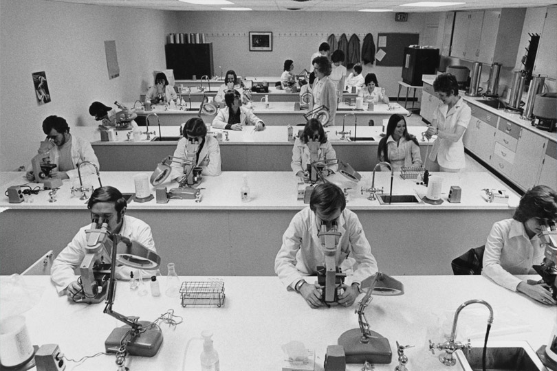 Students in the classroom in 1968 looking into microscopes