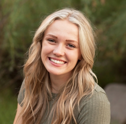 Smiling woman with long blond hair, wearing a green sweater.