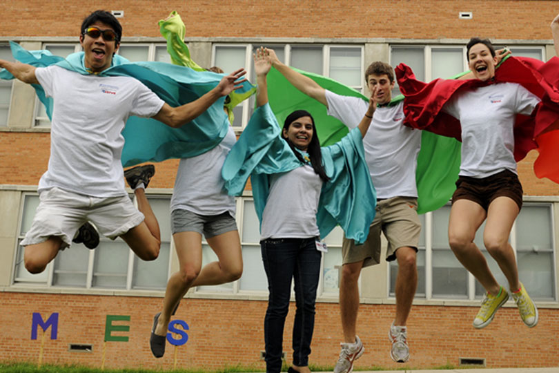 Five students leap into the air while wearing capes at United to Serve.