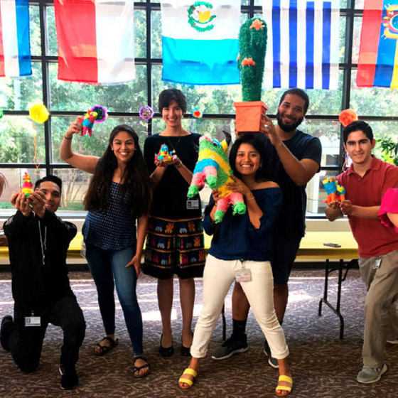 Three male students and three female students hold pinatas and other items from the Hispanic culture