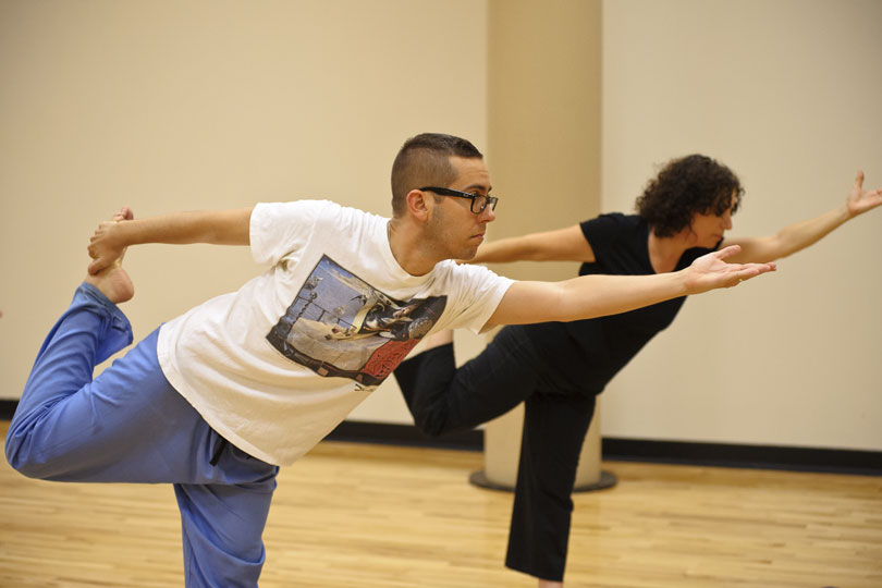 A man and a woman stand on one leg and stretch in the dancer pose during a yoga class m