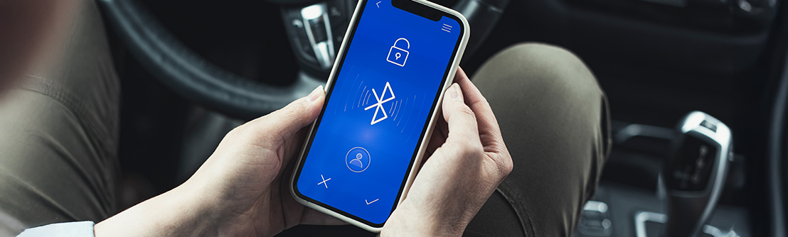 woman's hand holding smartphone with bluetooth logo on screen