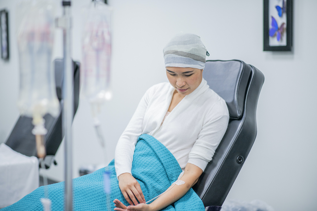 A patient sits receiving her intravenous chemotherapy drip treatment