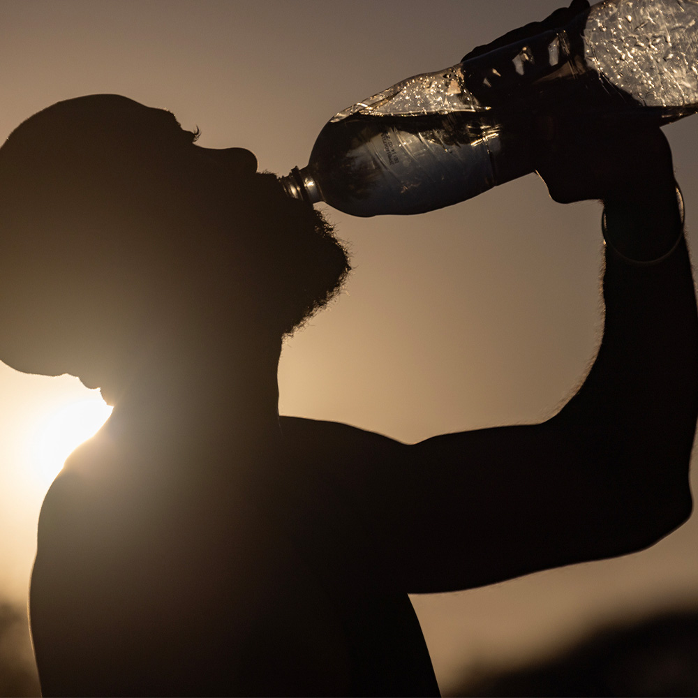 A man drinking water due to heat