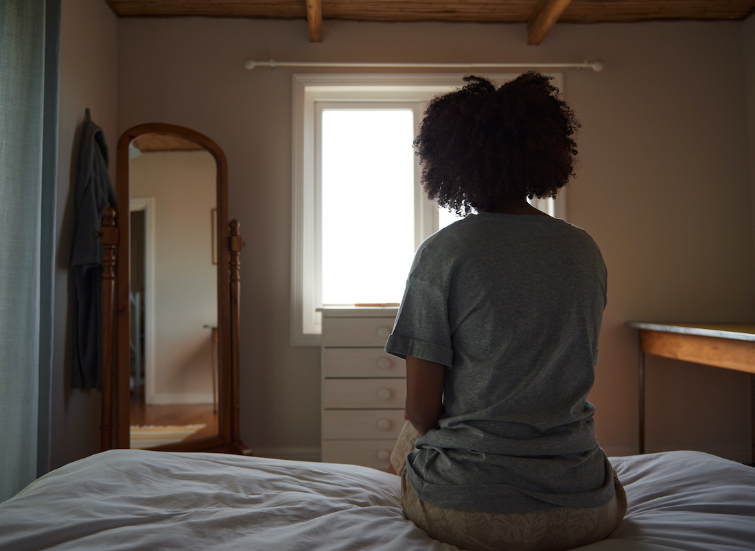 Young woman suffering from depression sitting in her bedroom
