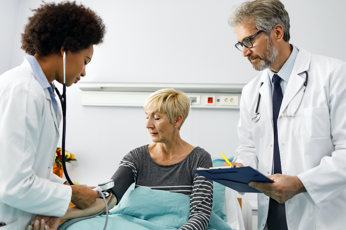 Female doctor checking blood pressure of a senior woman in a hospital