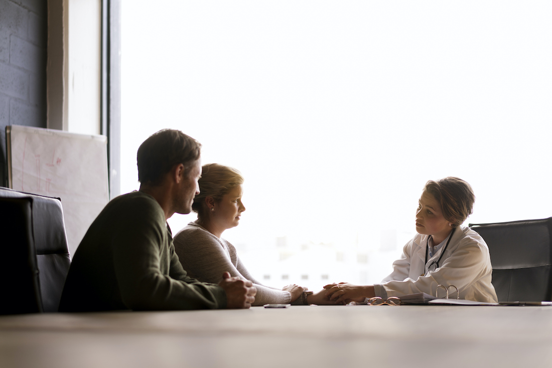 A photo of female doctor comforting couple