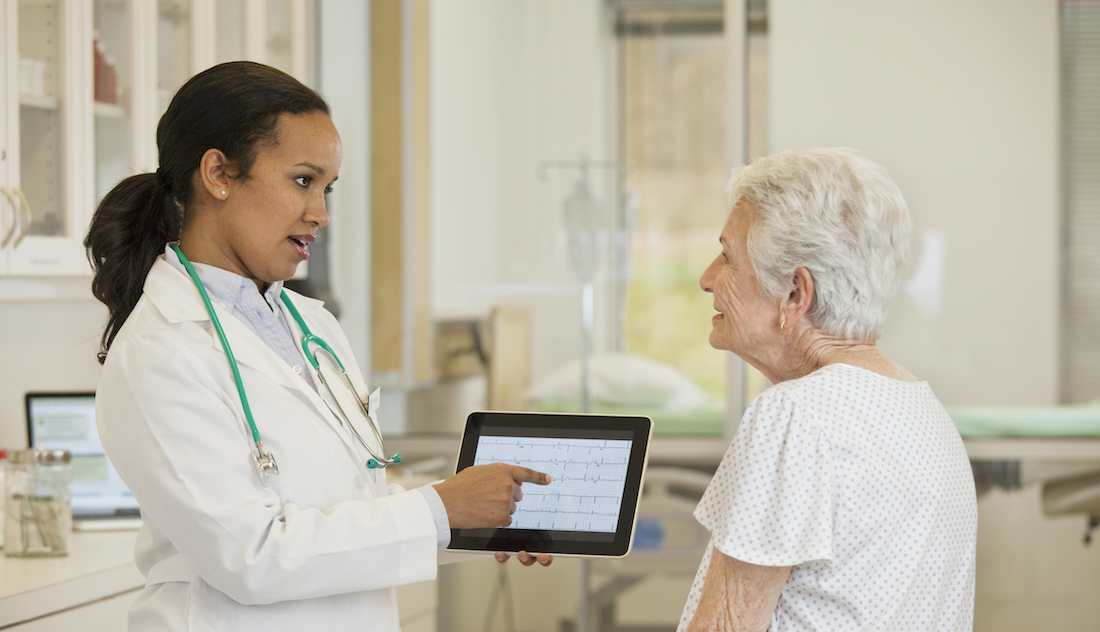 Doctor with digital tablet talking to patient