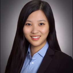 Dr. Amber Xie headshot: Asian woman with long dark hair, black blazer and blue shirt on gray background