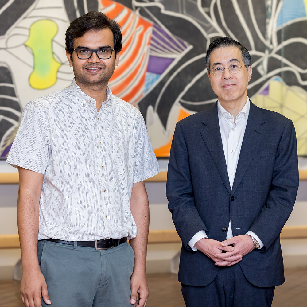 Dr. Ambarish Pandey and Dr. Thomas Wang standing in a hallway in front of a painting