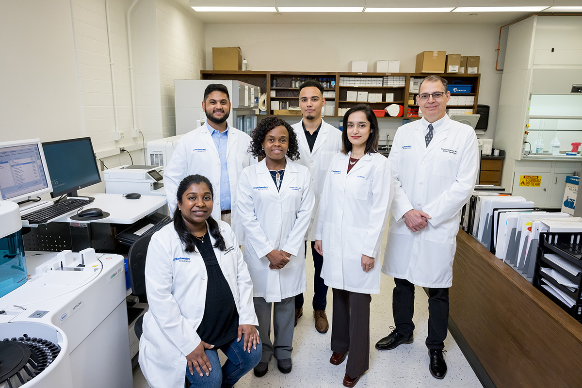 	three women and three men in a laboratory wearing white lab coats