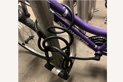 Front wheel of a purple locked to a bike rack