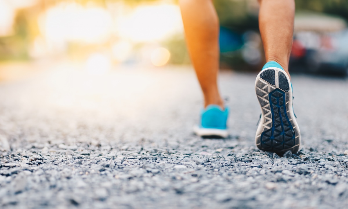 photo showing a runner's shoes on the pavement while running